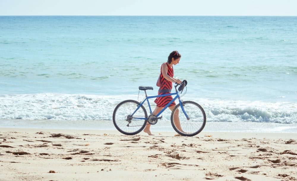 woman walking on anna maria island beach with a bike